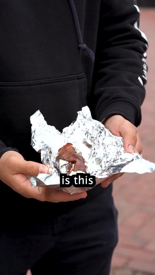Frame from the pizza video at thirteen seconds, hands opening a foil-wrapped dessert